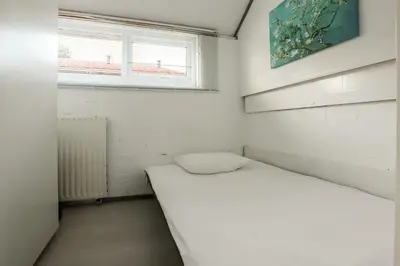 a small white room with a bed and a window at Rekerlanden 90 in Schoorldam