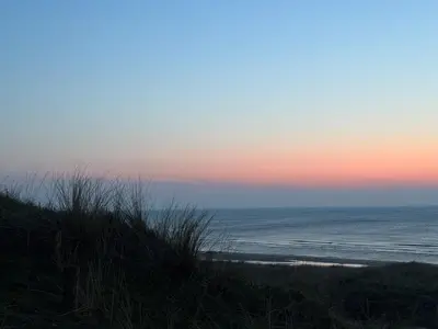 a view of the ocean from a beach at sunset at Vakantiewoning aan de Kust 16 in Egmond aan Zee
