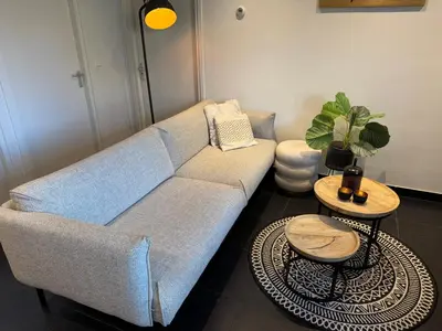 a living room with a blue couch and two tables at Vakantiewoning aan de Kust 16 in Egmond aan Zee