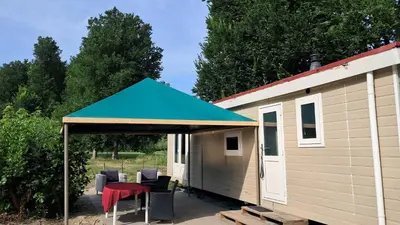 a shed with a blue roof with chairs and a table at Beemster b&b in Zuidoostbeemster