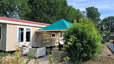 a small house with a blue awning next to a bush at Beemster b&b in Zuidoostbeemster