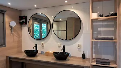 two sinks in a bathroom with two mirrors at Beemster b&b in Zuidoostbeemster