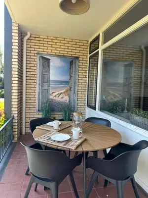 a patio with a wooden table and chairs on a porch at Zee & Zand in Noordwijk
