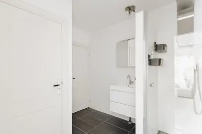 a white bathroom with a sink and a mirror at Luxurious Private Studio Amsterdam Zuid in Amsterdam