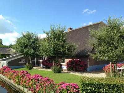 a house with pink flowers in the yard at De Porrel Polsbroek Unit met Privé Jacuzzi, Spa en Sauna in Polsbroek