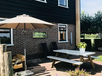 a picnic table with an umbrella and a bench at Logies De Hooiberg in Lutjewinkel