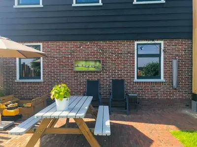 a picnic table and chairs in front of a brick building at Logies De Hooiberg in Lutjewinkel