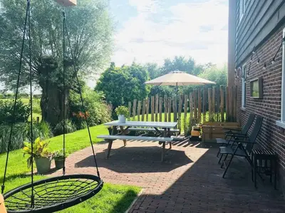 a patio with a picnic table and an umbrella at Logies De Hooiberg in Lutjewinkel