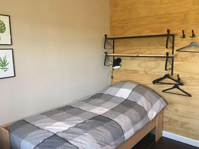 a bed in a room with hangers on the wall at Logies De Hooiberg in Lutjewinkel