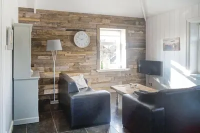 a living room with two chairs and a clock on a wall at Logies De Hooiberg in Lutjewinkel