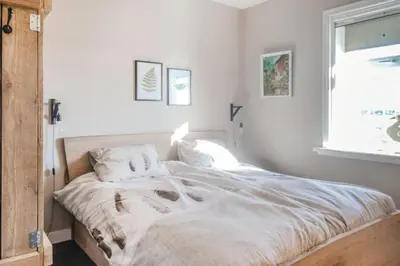 a white bed in a bedroom with a window at Logies De Hooiberg in Lutjewinkel