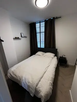 a bedroom with a white bed with a window at ‘T Singeltje in Leiden