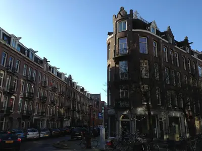 a tall building on a city street with parked cars at Boutique Amsterdam Homestay in Amsterdam
