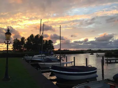 a group of boats docked in the water at sunset at Near Amsterdam, The Hague, Leiden and North Sea in Warmond