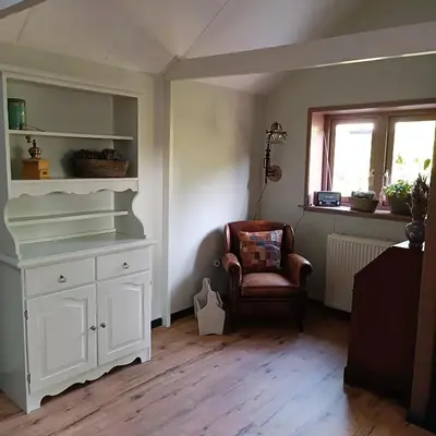 a room with a white cabinet and a chair at Vakantiewoning De Koolboet in Koedijk