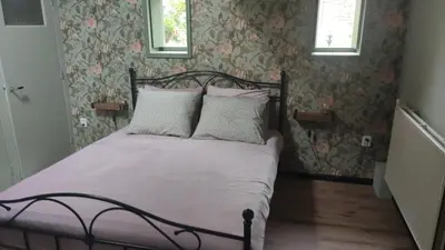 a bedroom with a bed with pink and white pillows at Vakantiewoning De Koolboet in Koedijk