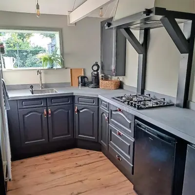 a kitchen with black cabinets and a stove top oven at Vakantiewoning De Koolboet in Koedijk