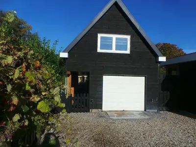 a black house with a white garage door at Top appartement in prachtige hart van Nederland Kortenhoef in Kortenhoef