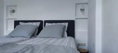 a white bedroom with a bed with two pillows at B en B Sluisje 1818 in Utrecht