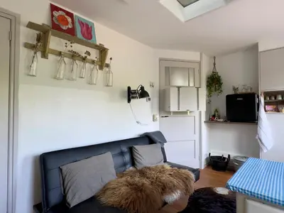 a living room with a black leather couch and a refrigerator at B en B Sluisje 1818 in Utrecht