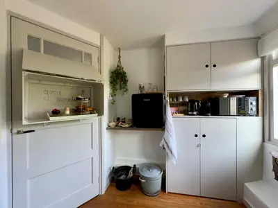 a kitchen with white cabinets and a door at B en B Sluisje 1818 in Utrecht