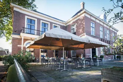 a patio with tables and chairs and umbrellas in front of a building at Boutique Hotel Brasa Beemster in Middenbeemster