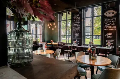 a restaurant with tables and chairs and a vase with flowers at Boutique Hotel Brasa Beemster in Middenbeemster