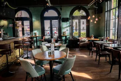 a restaurant with tables and chairs and windows at Boutique Hotel Brasa Beemster in Middenbeemster