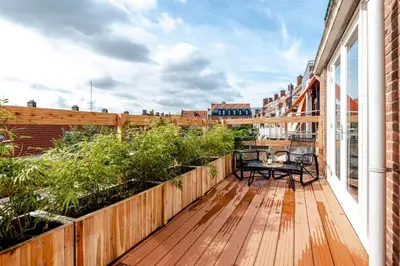 a wooden deck with a table and chairs on a balcony at Windhoek Apartment in Zandvoort