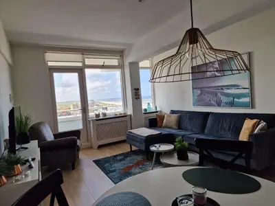 a living room with a blue couch and some tables at Beach & Sea view in Zandvoort