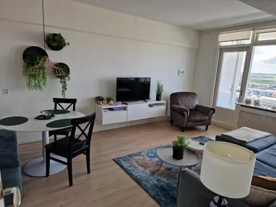 a living room with a table and chairs and a tv at Beach & Sea view in Zandvoort