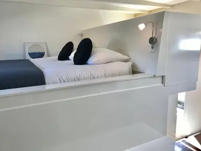 a small bedroom with a bed in a cabinet at Quiet Waterloft near Amsterdam and Schiphol WS17 in Aalsmeer