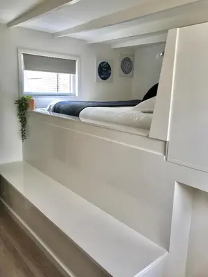 a white bedroom with a bed and a window at Quiet Waterloft near Amsterdam and Schiphol WS17 in Aalsmeer