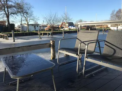 two chairs and a table sitting on a deck at Quiet Waterloft near Amsterdam and Schiphol WS11 in Aalsmeer