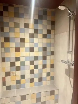 a bathroom with a shower with a tiled wall at Luxe in stiltegebied tussen loslopende Alpaca’s in Eemdijk