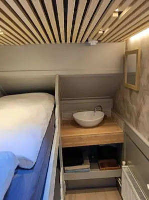 a bathroom with a bed and a sink in a room at Boutique style ship 10 double cabins in Monnickendam