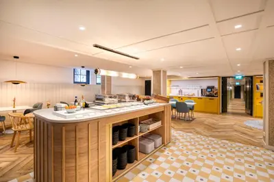a kitchen and dining room with yellow cabinets and a counter at Citadines Canal Amsterdam in Amsterdam