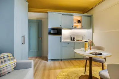 a kitchen with blue cabinets and a table in a room at Citadines Canal Amsterdam in Amsterdam