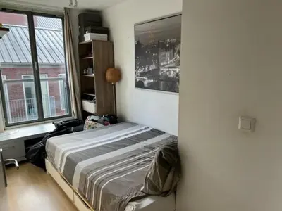 a bedroom with a bed in a room with windows at center appartement 2 rooms in Alphen aan den Rijn