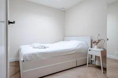 a white bedroom with a white bed and a table at Dunefront Apartment in Zandvoort