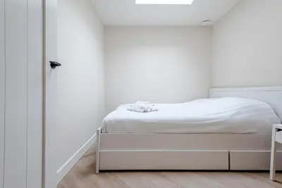 a white bedroom with a bed and a closet at Dunefront Apartment in Zandvoort