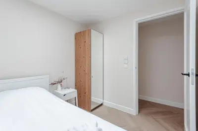 a bedroom with a white bed and a wooden closet at Dunefront Apartment in Zandvoort