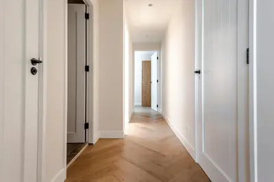 an empty hallway with white walls and wood floors at Dunefront Apartment in Zandvoort
