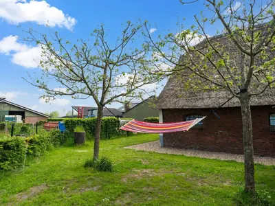 a hammock in a yard next to a house at Farmhouse with terrace in Montfoort in Montfoort