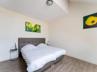 a bedroom with a bed with white sheets and two paintings at Farmhouse with terrace in Montfoort in Montfoort