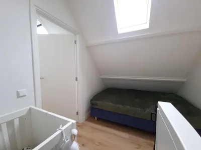 a small attic bedroom with a bed and a window at De Witte Vos in Egmond aan Zee