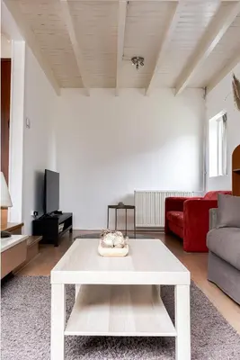 a living room with a white table and a red couch at - Het Kleine Nest - nabij het meer, strand & Keukenhof in Noordwijkerhout