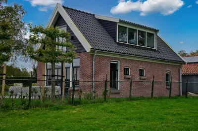 a red brick house with a black roof at Het Gouwe Boetje in Hoogwoud