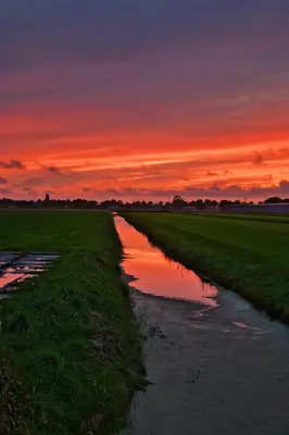 a sunset over a river in a field at Het Gouwe Boetje in Hoogwoud
