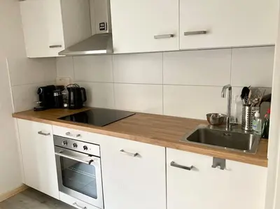 a white kitchen with a sink and a stove at Cosy beach house for ocean & nature lovers in Noordwijk